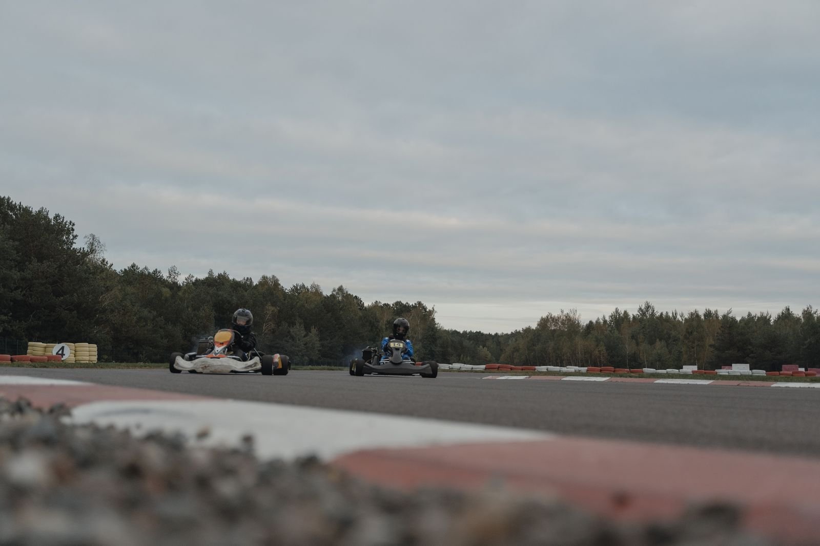 Two go-karts racing wheel to wheel on an outdoor kart circuit